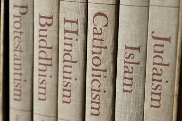 Book spines listing major world religions