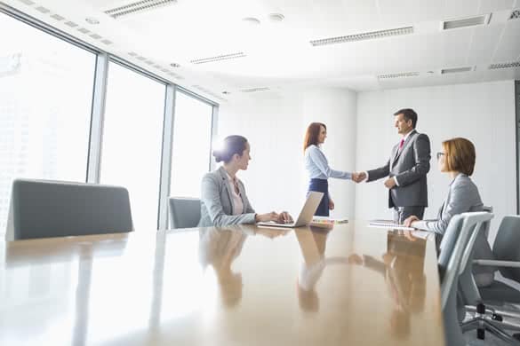 Businessman and businesswoman shaking hands in conference room