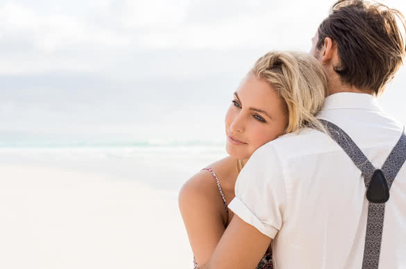 Close up face of a young woman embracing her boyfriend at beach