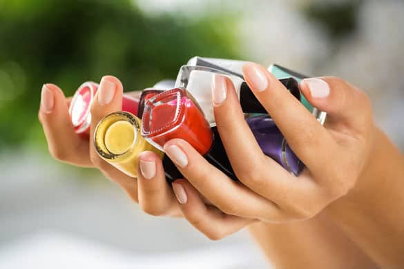 Close up of woman hands with nail polishes of different colors