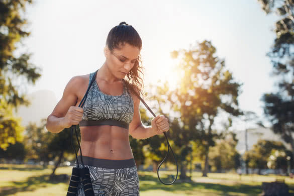 Fit young woman holding a skipping rope around her neck