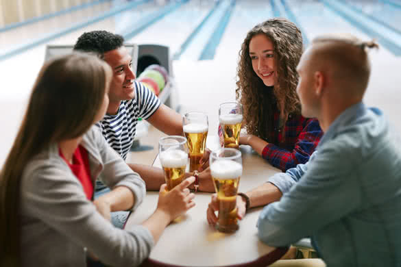 Group of friends drinking beer in bowling club