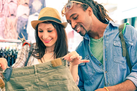 Interracial young couple searching clothing at street shop market