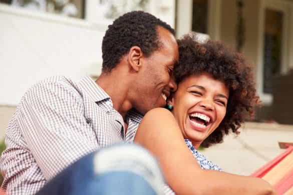 Laughing couple cuddling in a hammock