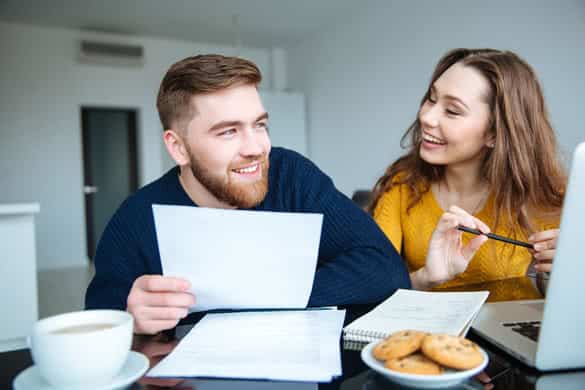 Portrait of a cheerful young couple calculating their bills at home