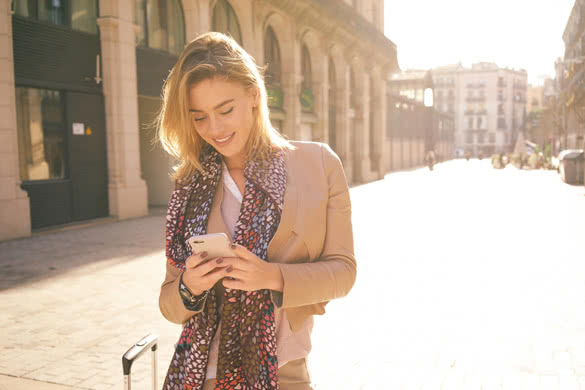 gorgeous beautiful young woman with blonde hair messaging on the smart-phone at the city street background