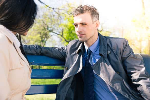 Portrait of a beautiful couple talking on the bench outdoors. Looking at each other