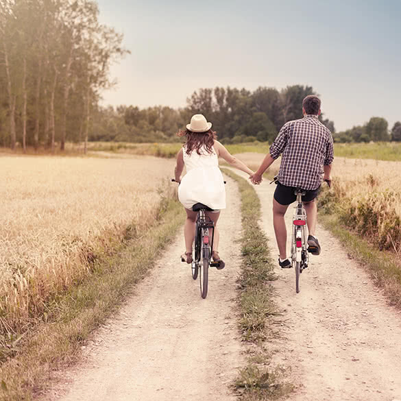 couple riding bikes and holding hands