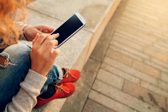 Beautiful young hipster woman using smart phone at beach