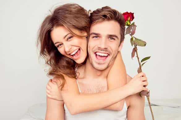 Cheerful young couple in love embracing in the bedroom with rose