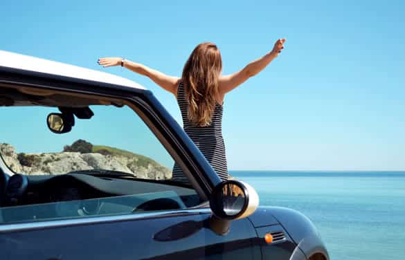 Happy beautiful blond young woman driving a sports car