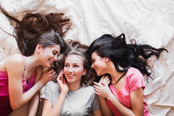 Top view of three best friends tell secrets in bed