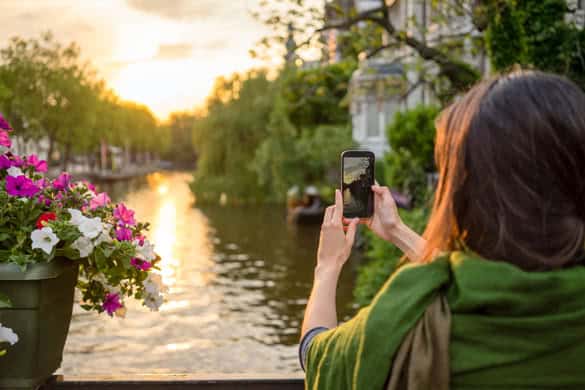 a tourist young women in Amsterdam take pictures at a beautiful sunset on a bridge