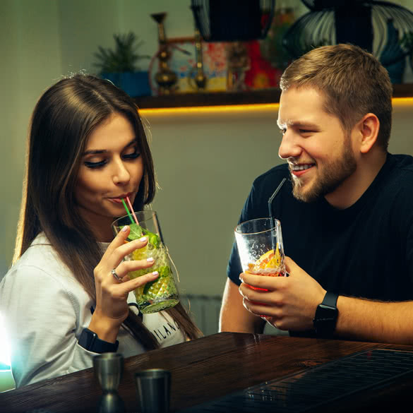 attractive couple flirting and drinks cocktails at the bar