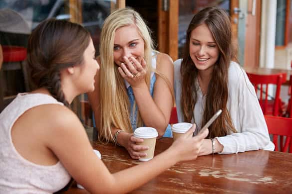 beautiful young girls having coffee at outdoor cafe with mobile cell phone