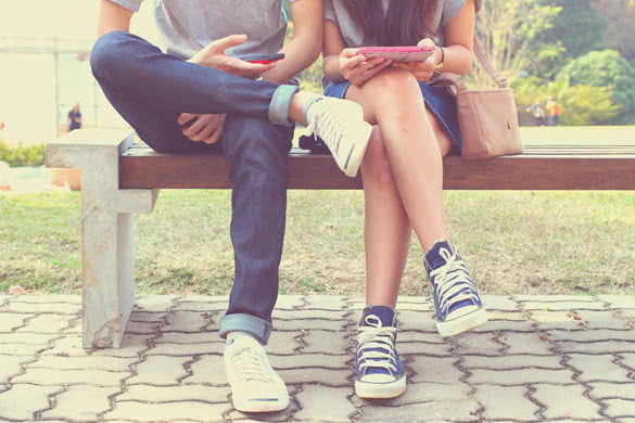 Close up of hipster couple in disinterest moment with smart phones in the outdoor