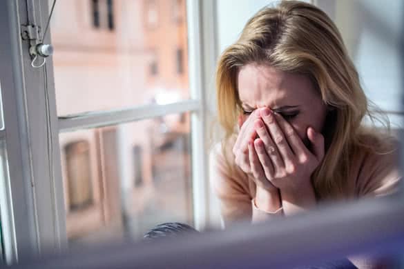 Woman sitting on windowsill and crying