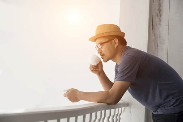 Young hipster man resting at home balcony with the sunrise