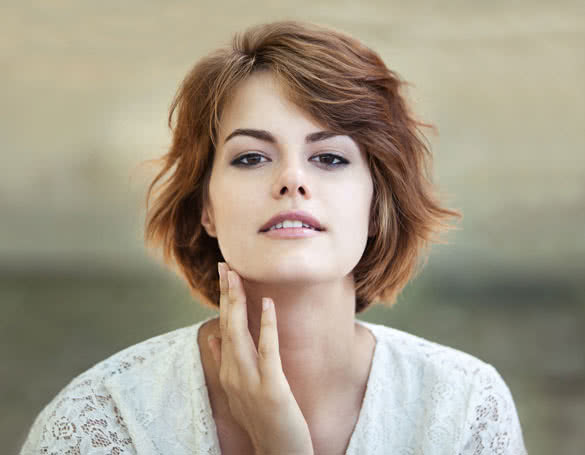 Beautiful young girl smiling and touching her face with her hand