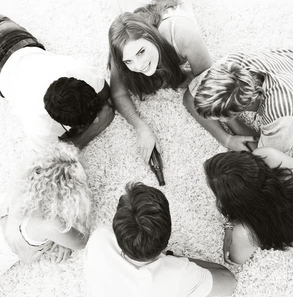 Group of friends lying on the floor and playing spin the bottle