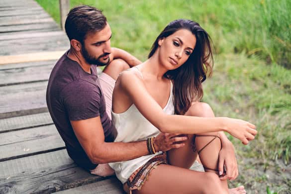 Man looking at his girlfriend sadly while she is fixing her hair