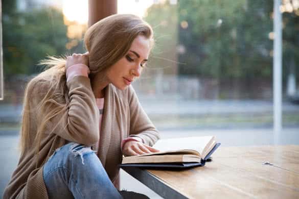 Portrait of a beautiful girl reading book in cafe