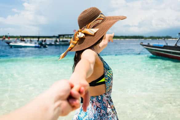 Woman wanting her man to follow her in vacation or honeymoon to beach by the ocean