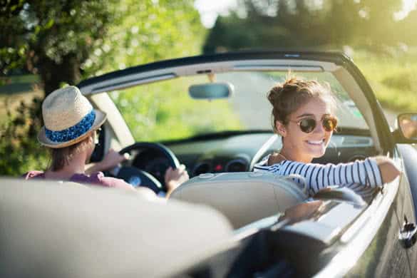 Young trendy couple happy to drive his convertible car on a country road in summer