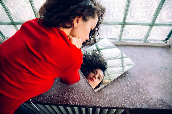 dreamy look of a young woman with curly hair in a mirror