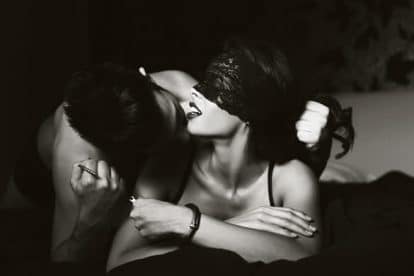 woman in lace eye cover with young lover in hotel room
