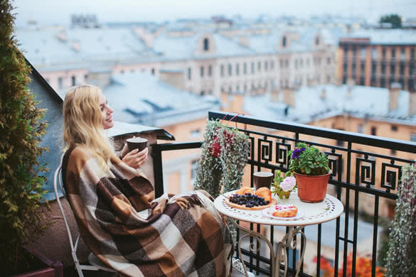 woman with tea sheltered blanket breakfast on the balcony overlooking the city