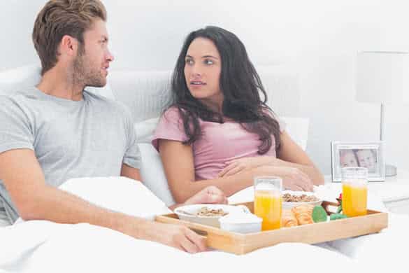 Couple looking at each other during breakfast in their bed