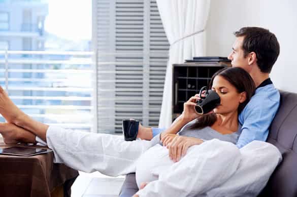 Couple relax at home with cup of coffee and sofa couch