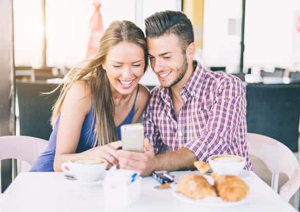 Happy couple in a coffee house having breakfast and photographing themselves