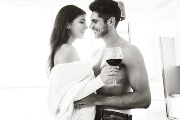 Happy tender young couple drinking red wine together at home