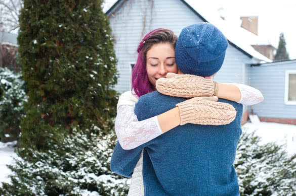 Happy young couple hugging in front of the house