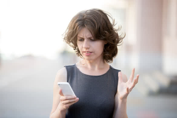 Portrait of young woman holding cellphone in hands on the street in summer