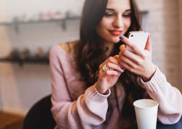 Woman typing write message on smart phone in a modern cafe