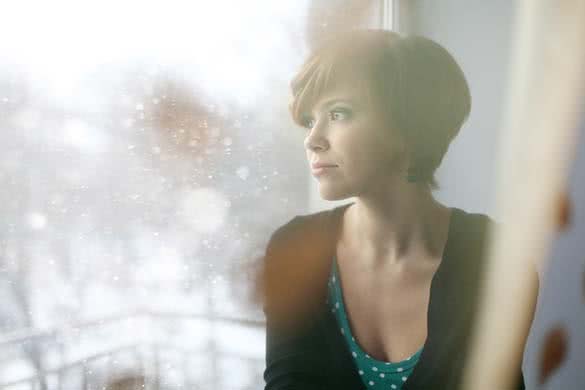 woman sitting by the window thinking