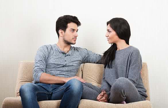 young couple sitting on a couch and talking