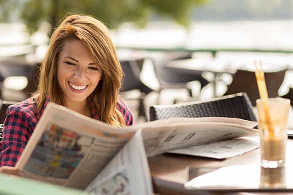 young brunette enjoying coffee and reading newspapers