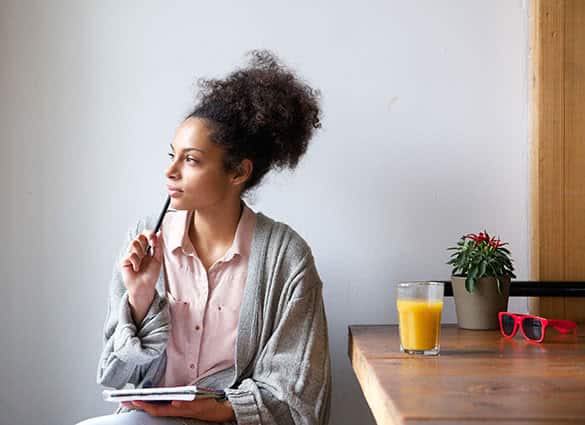 young woman writing and thinking